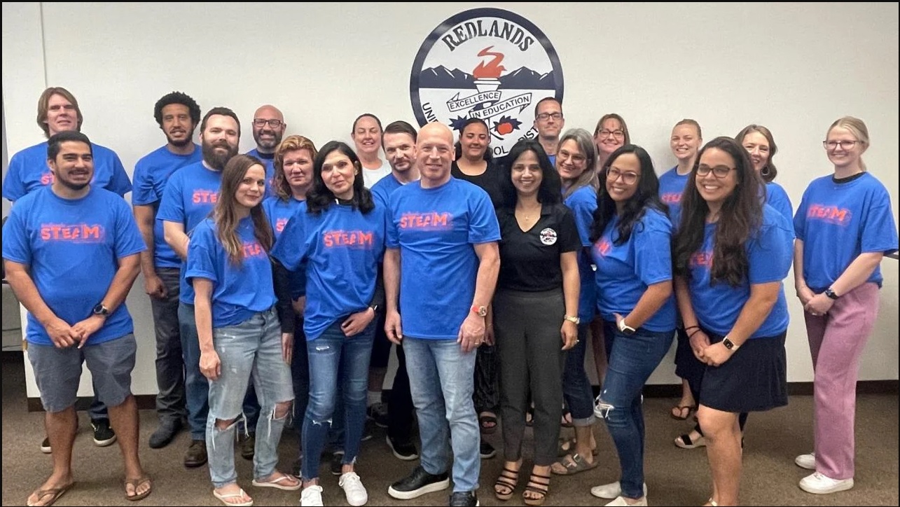 A group of teachers wearing blue T Shirts pose for a group photo