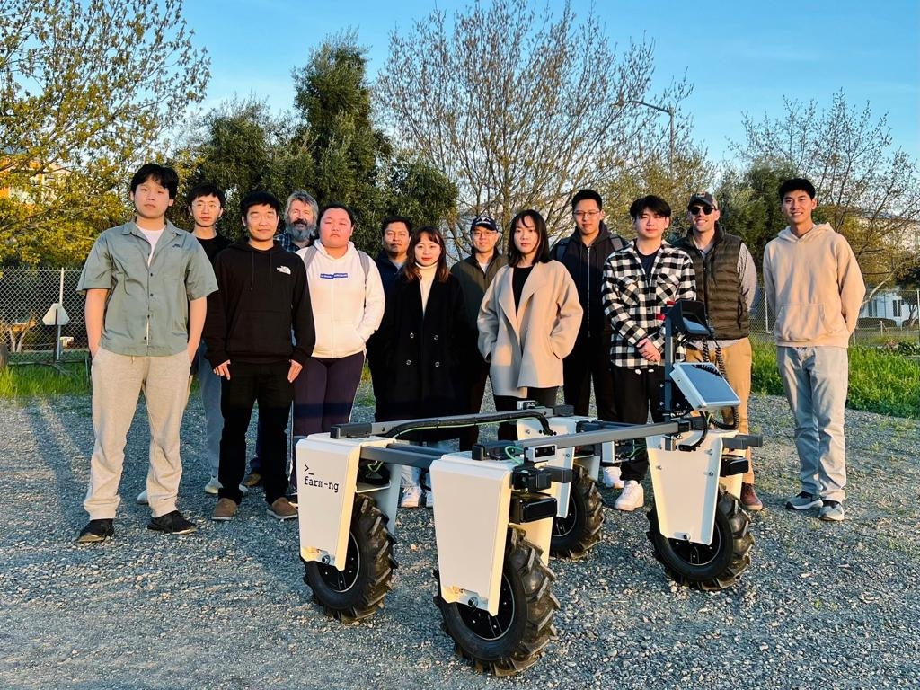 Students stand in a field with a robot