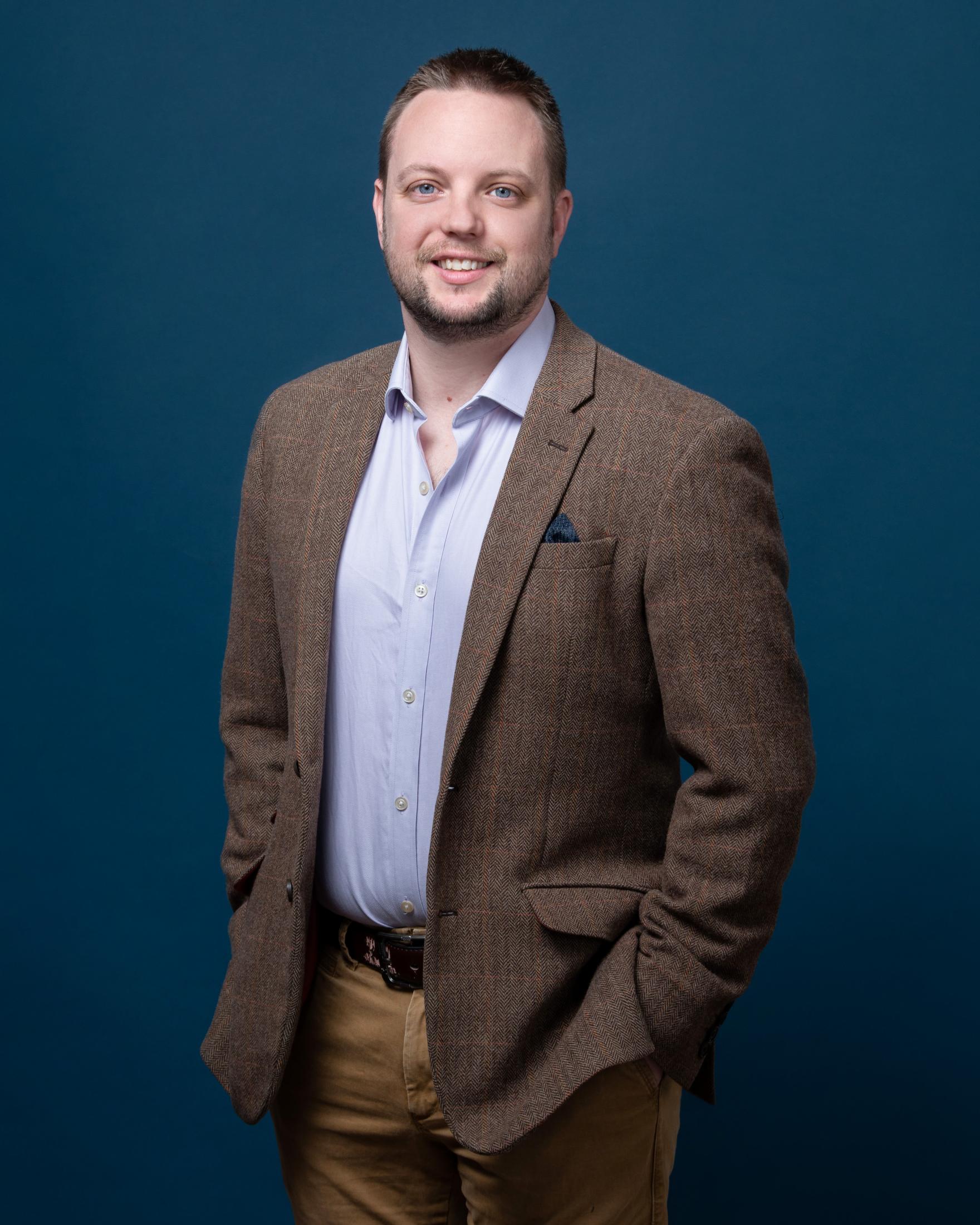 Rich Whittle poses against a blue background