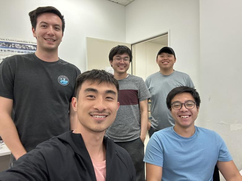 Five students pose for a group photo indoors