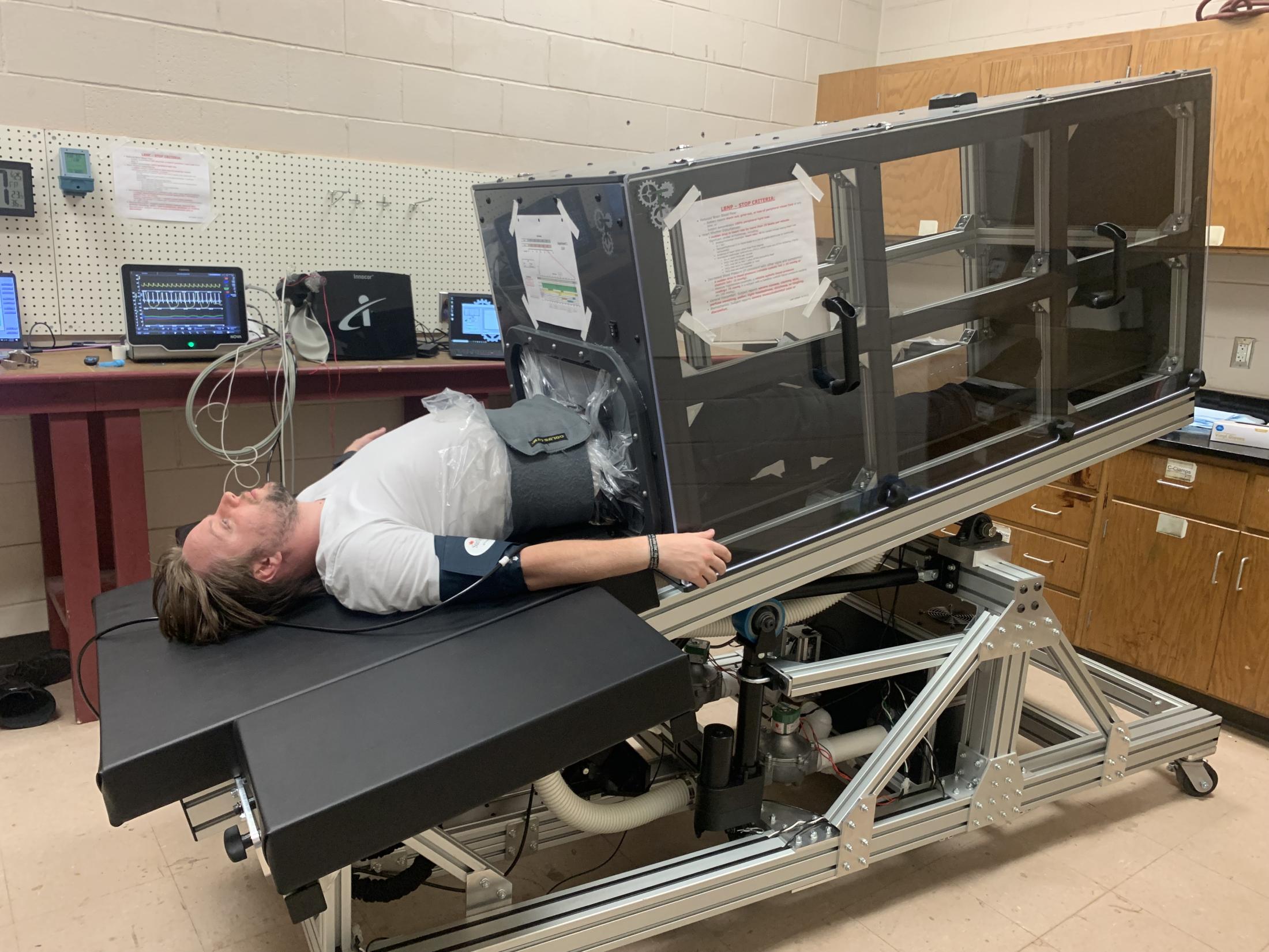 Person lays down in a body negative pressure chamber