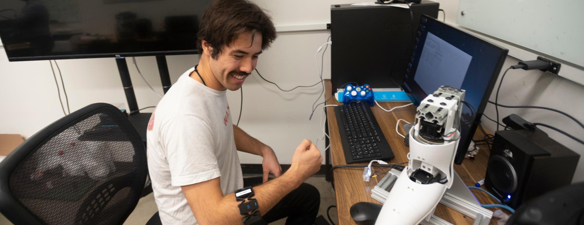 A young man sitting at a desk and wearing an armband
