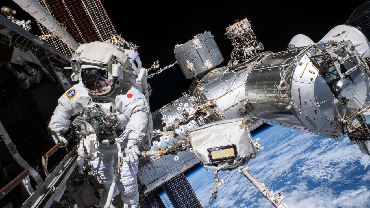 Astronaut wearing space suit floats outside of the International Space Station, in space 