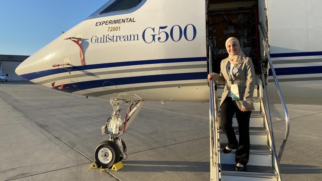 UC Davis student Duha Bader stands on steps of an airplane