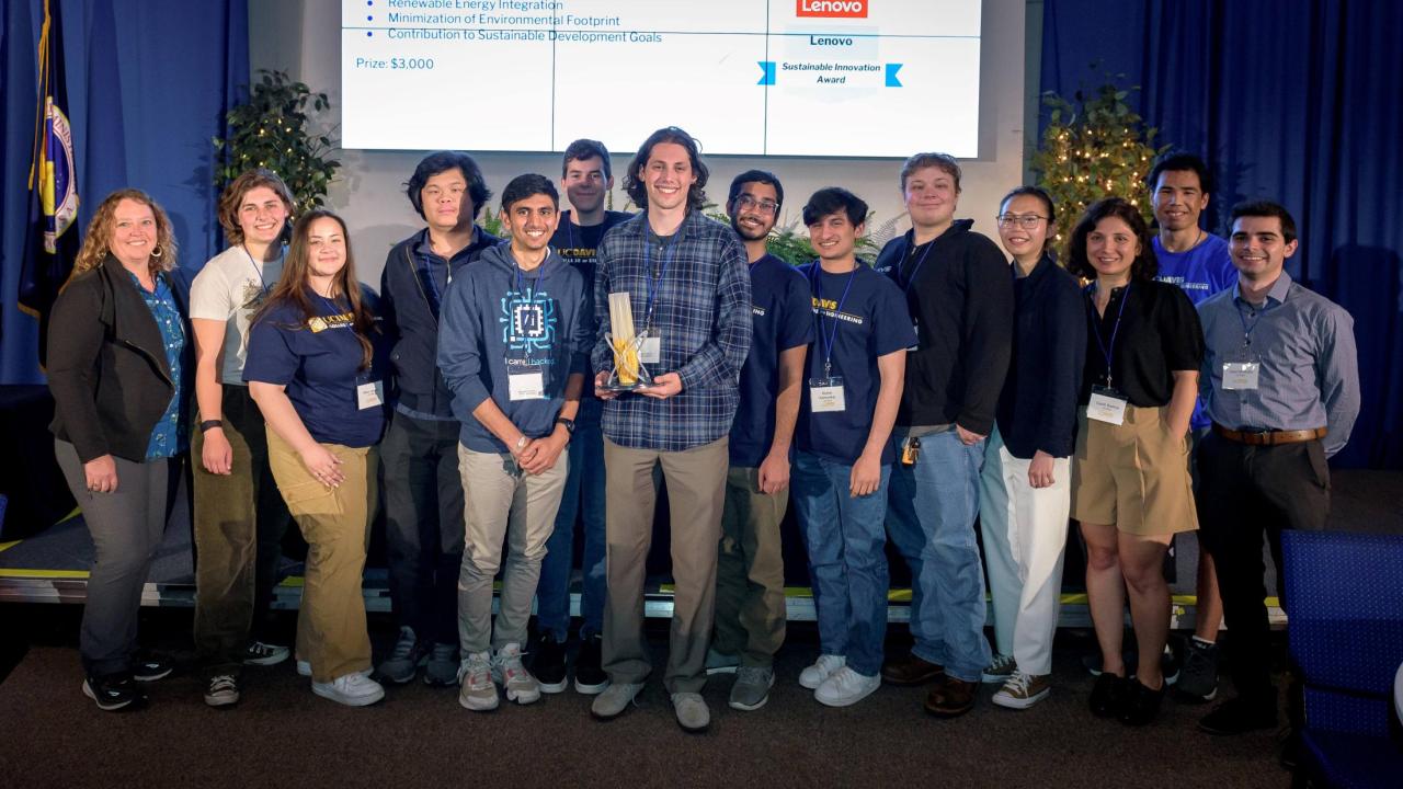 A team of students with a trophy on a stage