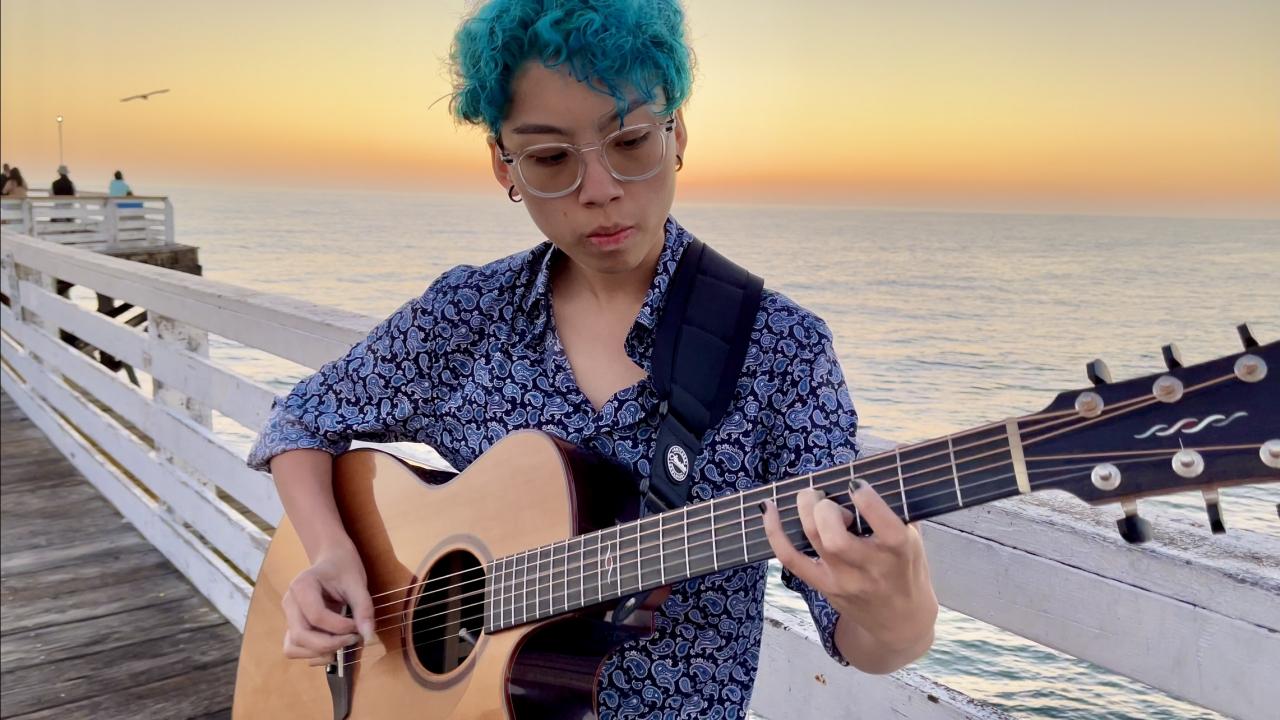 Kat Gallardo playing the guitar at the San Diego Pacific Beach Crystal Pier