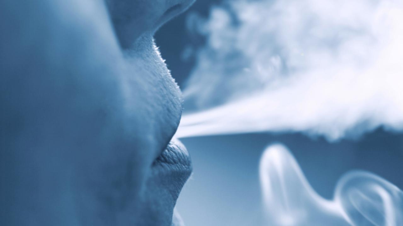 A person blowing smoke out of their mouth