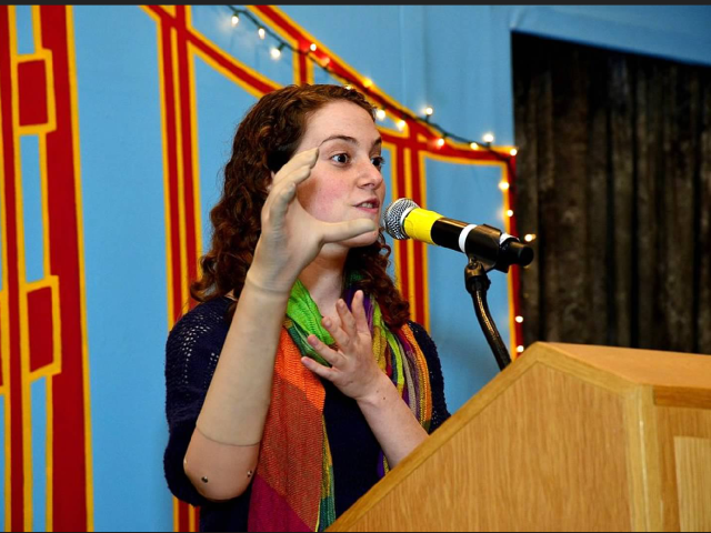 Tal Oppenheimer speaks at a wooden podium