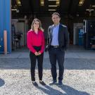 Assistant Professor Shima Nazari and Assistant Professor Iman Soltani stand together in front of the open bay doors of the Advanced Highway Maintenance and Construction Technology Research Center at UC Davis