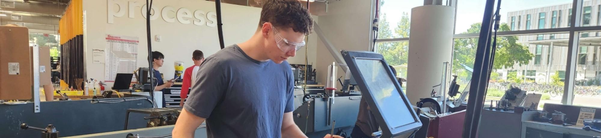 Student works on machinery in the Engineering Student Design Center at UC Davis